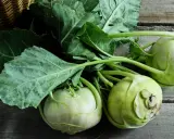 Frische Kohlrabi mit grünen Blättern liegen auf Holz. Vielleicht ein Leckerbissen für ein Kaninchen?