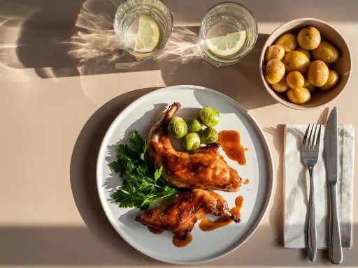 Gebratenes Kaninchen mit Rosenkohl, Petersilie und kleinen Kartoffeln, serviert mit Zitronenwasser.